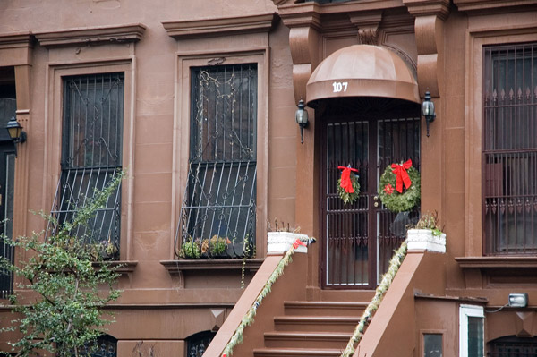 Steps on a brownstone lead to its door, with two Christmas
wreaths.