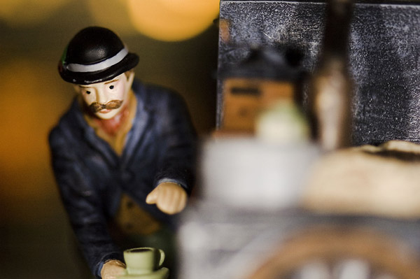 A figurine draws a mug of coffee from a tap.