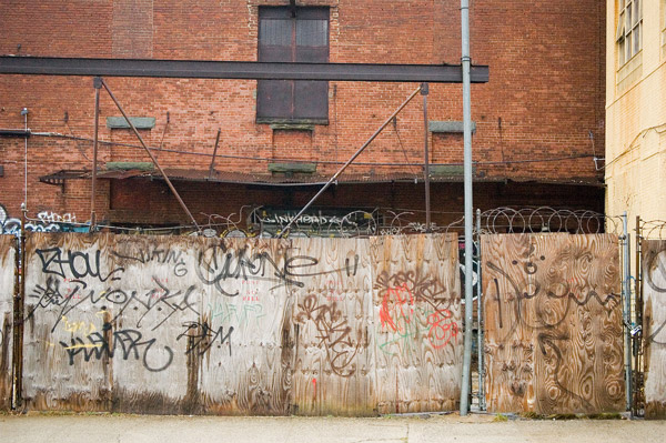 An industrial fence, made of plywood and barbed wire.