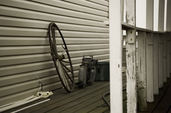 A wheel leans against the outside wall of a fishing cabin.