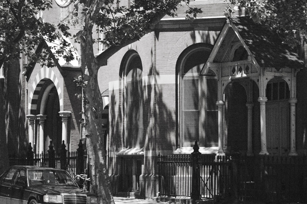 Shadows of trees dominate a church-like structure.