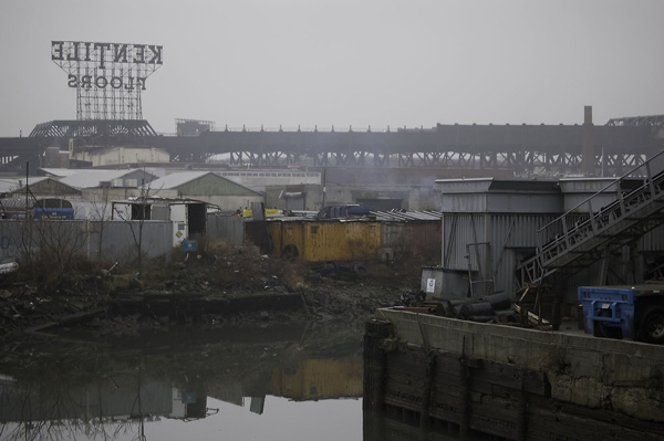 A sign for Kentile Floors overlooks an elevated train and
the Gowanus Canal.