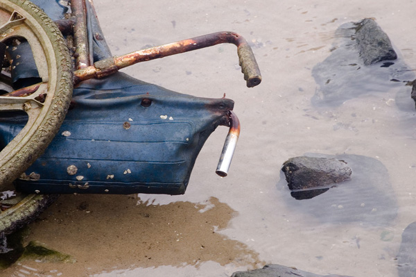 A rusted wheelchair sits in six inches of water.