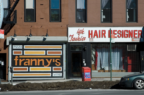 Two storefronts, one with a sign in disrepair.