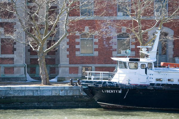 A boat is moored next to an off-limits Ellis Island
building.