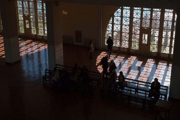Light shines through a reticulated window, into a large hall.