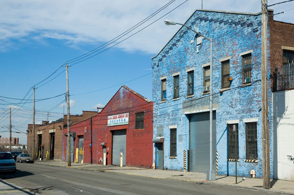 A street with low-rise industrial brick buildings in broght
colors.