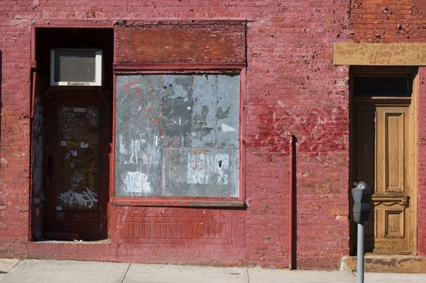 A brick building with a boarded-up display window.