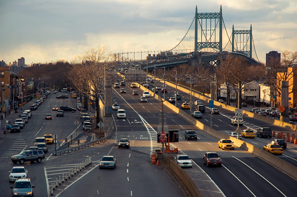 Sunset lights Astoria Boulevard and cars, bridge in the
distance.