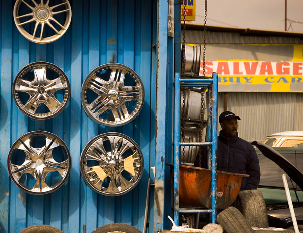 Wheel hubs decorate a wall, and a man stands around
the corner.