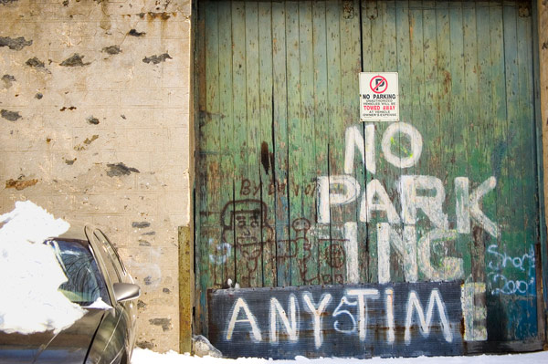 A green wooden garage door with 'No Parking' messily
painted on it.