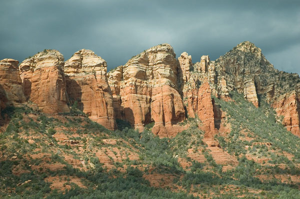 Mesas show their layers of rock, against a dark sky.