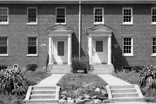 A pair of sidewalks lead up to brick homes.