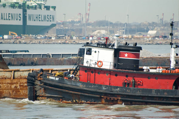 A red tugboat at work in the waters of New York harbor.