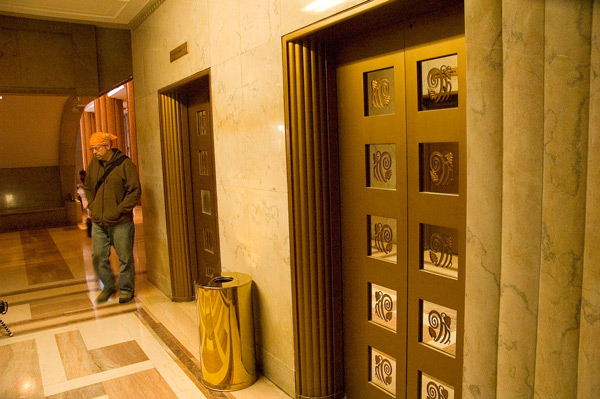 A man stares towards the floor in a glossy lobby.