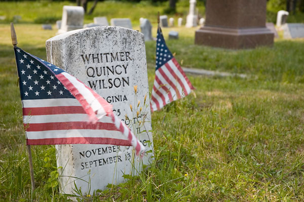 A military tombstone, of Whitmer Quincy Wilson, with flags
nearby.