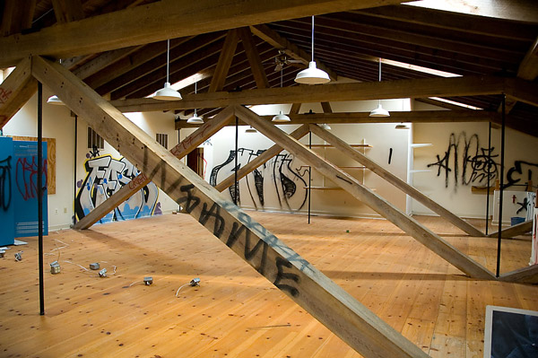 An empty attic room has graffiti all over.