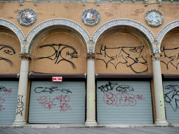 An old abandoned building with columns at the entrance,
festooned with tiles.