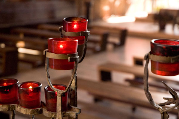 Votive candles in red glass are supported by cast-iron.