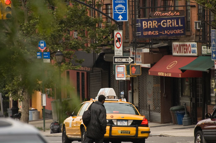 Street scene including a taxi cab, neon signs, and people.