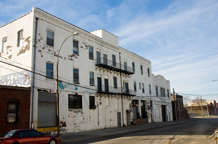 An old white building has a beautiful blue shy above it.