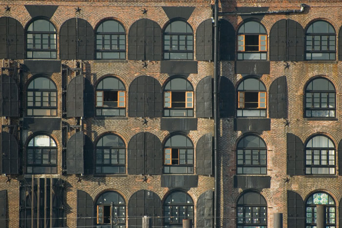 Shutters are open on the outside of a brick warehouse.