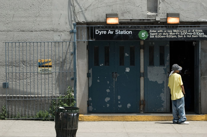 A youth in a yellow t-shirt outside a subway.