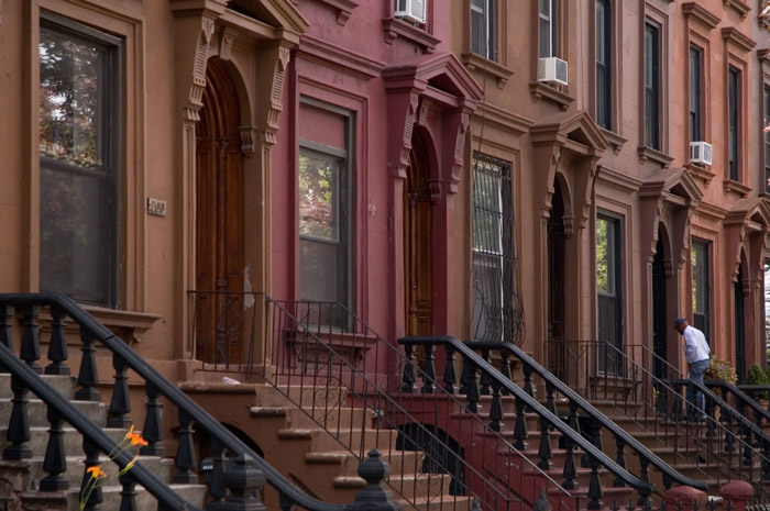 A man walks up the steps in a row of brownstones.