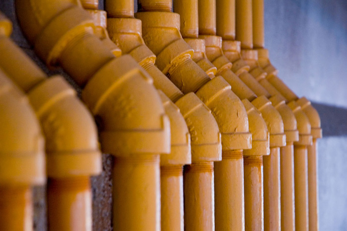 A row of jointed yellow pipes against a blue background.