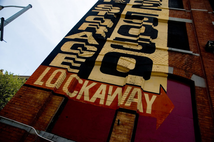 A sign on a building wall looks disjointed from below.