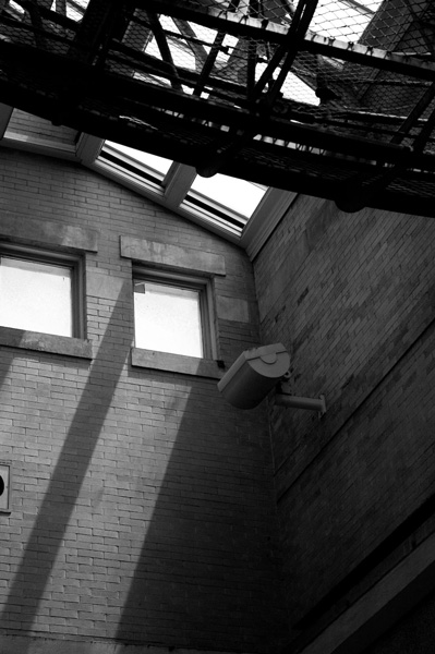 Shadows from a skylight grace a brick wall.