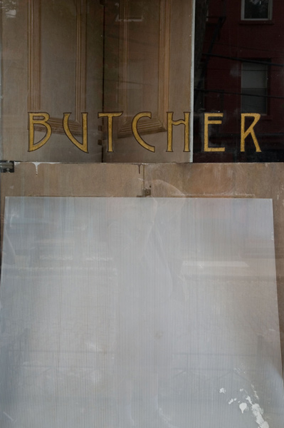 A painted gold leaf window sign reads 'Butcher.'
