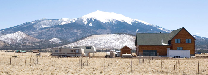 A reddish house with a snow capped mountain behind it.