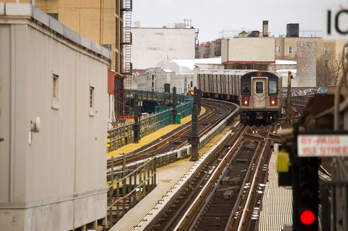 A subway train curves on a track, into a station.