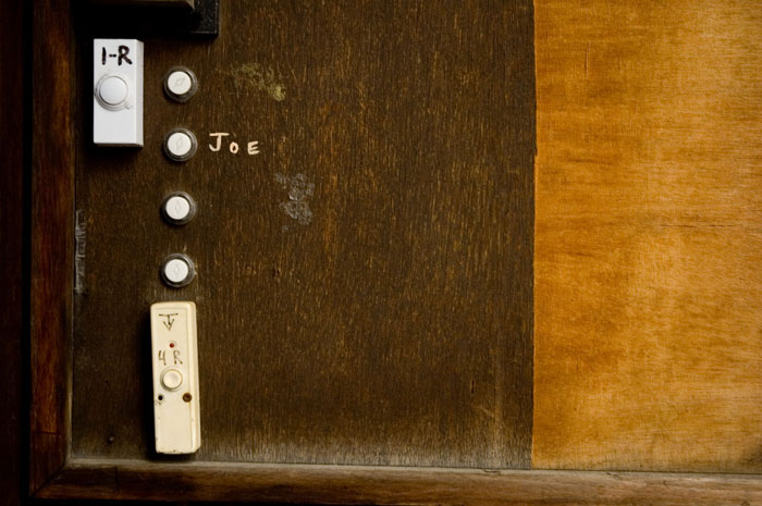 A group of door buzzers, against a wood background.