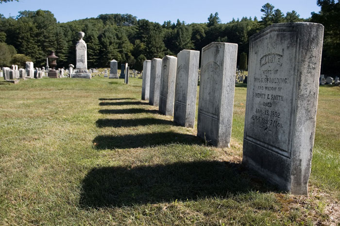 A row of tombstones and shadows create a vanishing point.