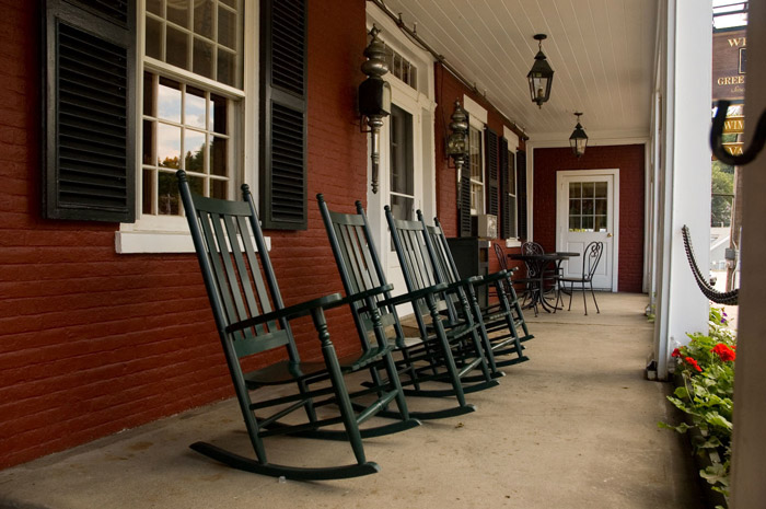 Four green rocking chairs lead to a door at the end or the
porch.