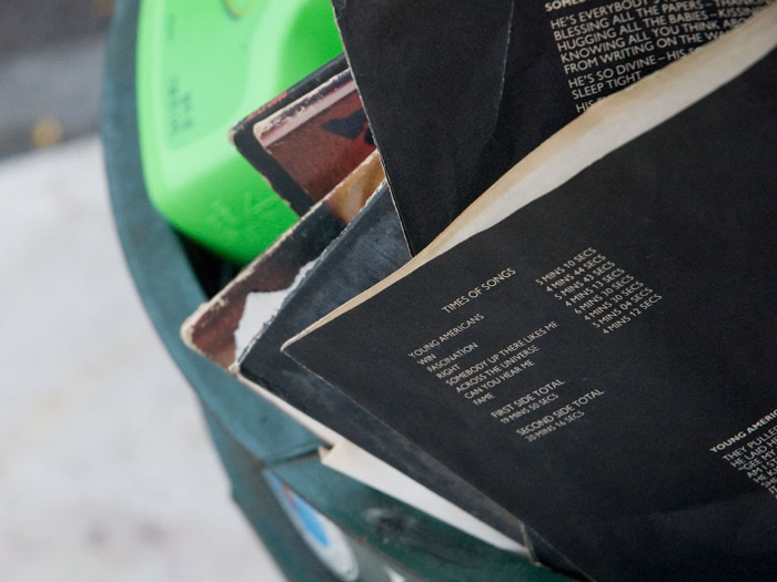 The paper sleeve of a David Bowie record curled in the trash.