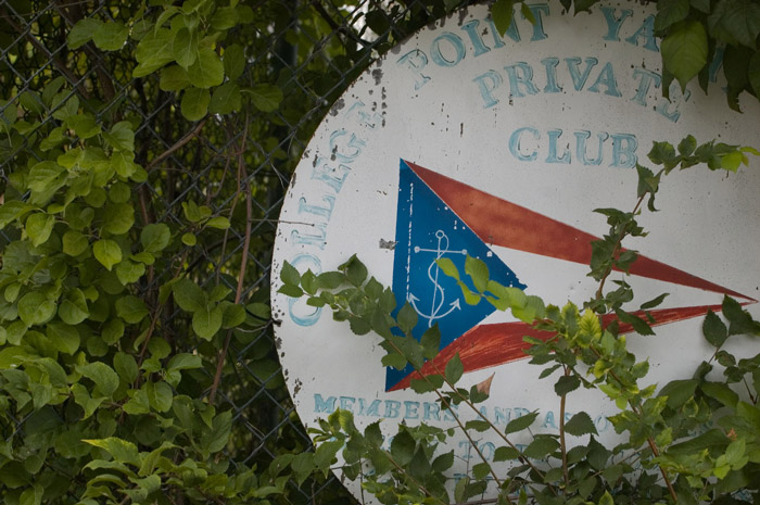 A sign for a neighborhood yacht club, obscured by ivy.