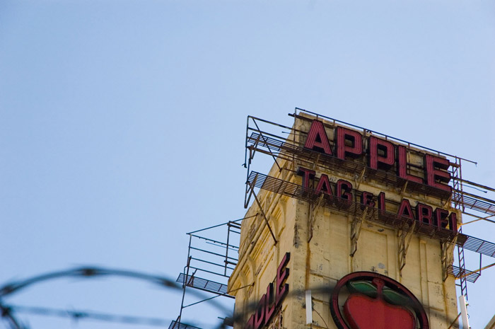 An old building tower, with electric signs and scaffolding.