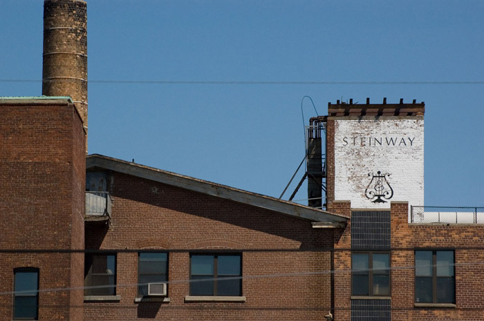 The word 'Steinway' and lyre logo dresses a brick building.