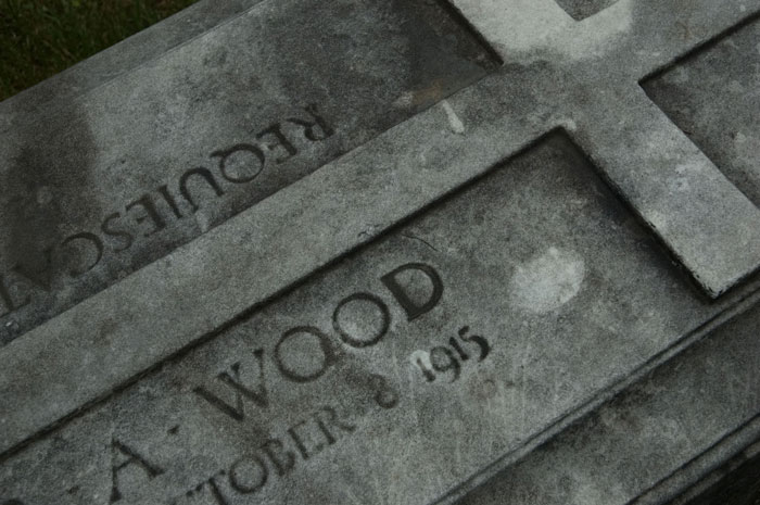 A stone tomb has a cross and name engraved on it.