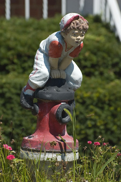 A statue of a boy leaping over a fire hydrant.