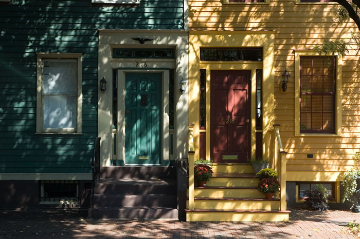 Brightly painted doors and their homes peak through shadows.