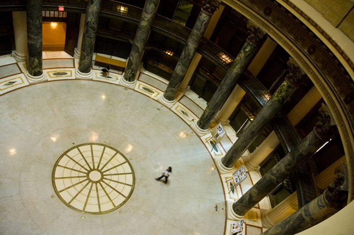 A solitary person walks into the circular space of a lobby.