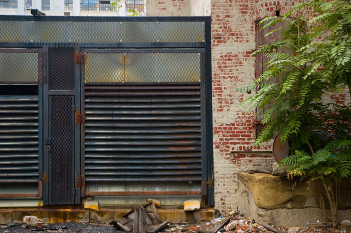 A complex wall of brick, steel grates, and louvered metal.