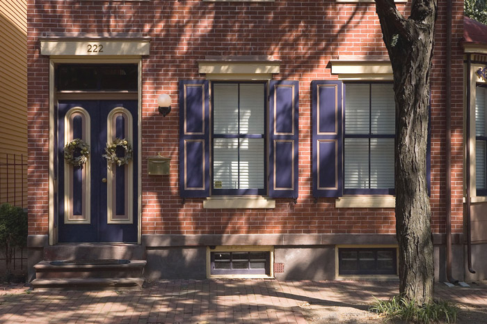 A brick-face house with a purple door and shutters.