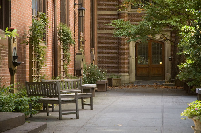 Benches and trees in a brick-walled courtyard.