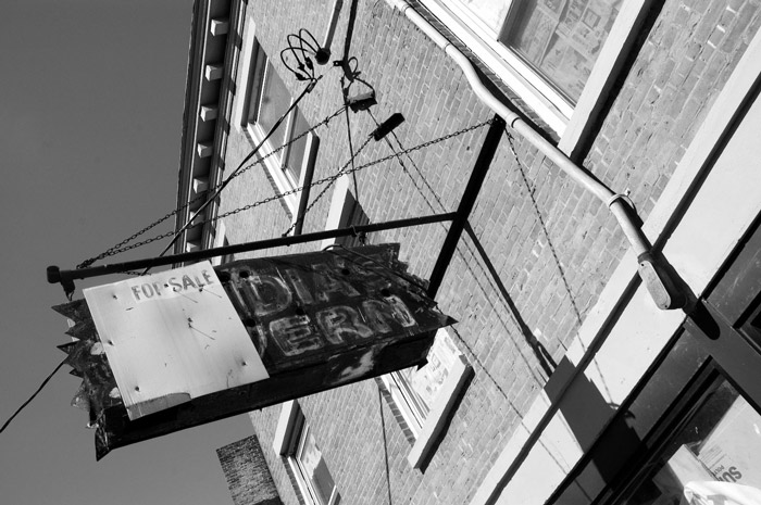 A 'For Sale' sign is overlaid on a rusty tavern sign.