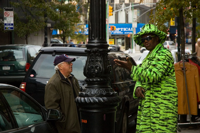 Two people talking, one in a green coat with tiger stripes.